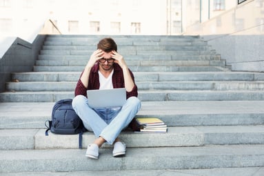 desperate-student-sitting-on-stairs-with-laptop-PZSGYKQ