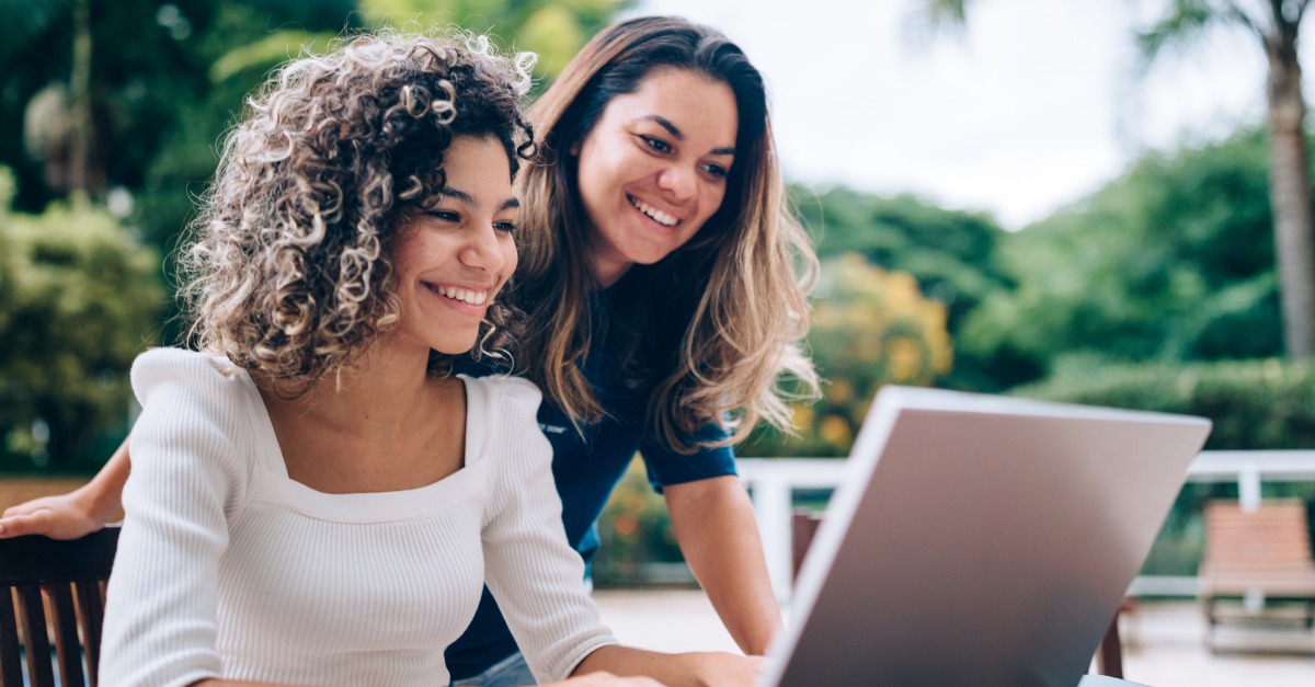 Two students looking at laptop outside
