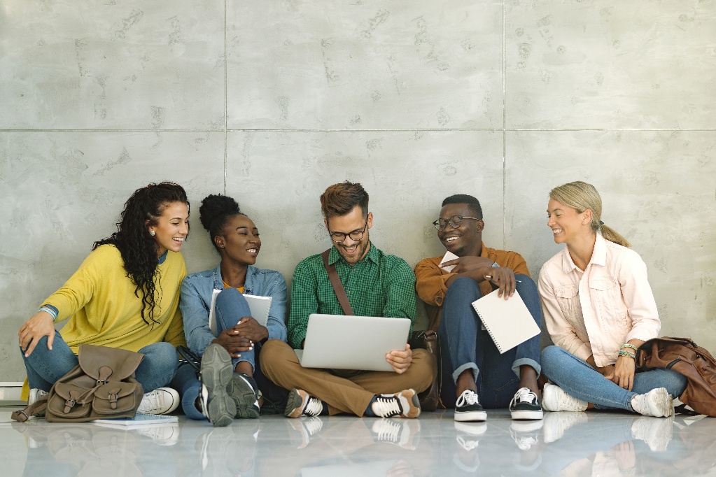 happy-university-students-using-laptop-while-sitting-hallway